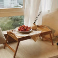 Bamboo bed tray with legs and handles set on a floor rug