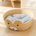 Round woven pet bed with a bear face and patterned cushion