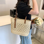 Rounded beige woven straw beach handbag with an adjustable strap