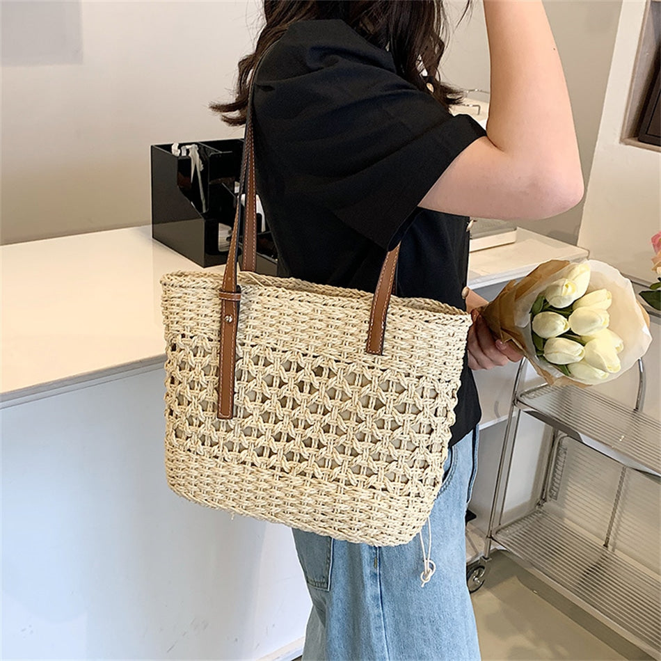 Rounded beige woven straw beach handbag with an adjustable strap