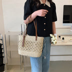 Rounded beige woven straw beach handbag with an adjustable strap