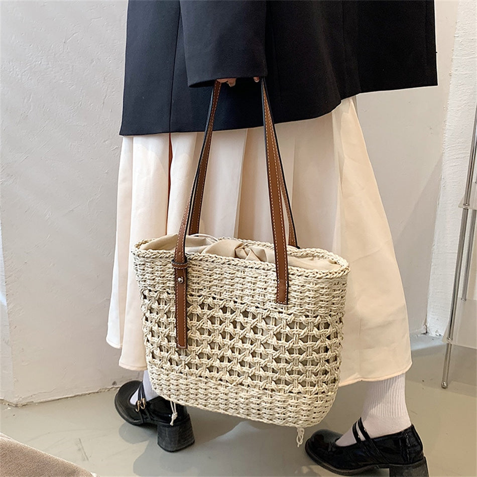 Rounded beige woven straw beach handbag with an adjustable strap