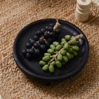 Round black wooden fruit bowl with visible wood grain