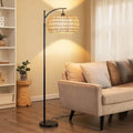 Boho floor lamp with a hand woven rattan shade on a slim black stand