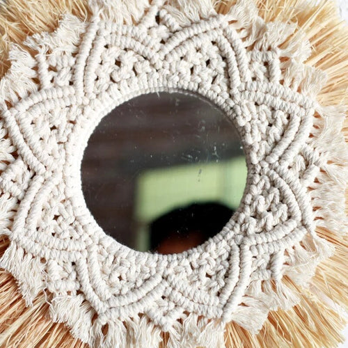 Round mirror framed by straw fringe and cotton macrame mandala