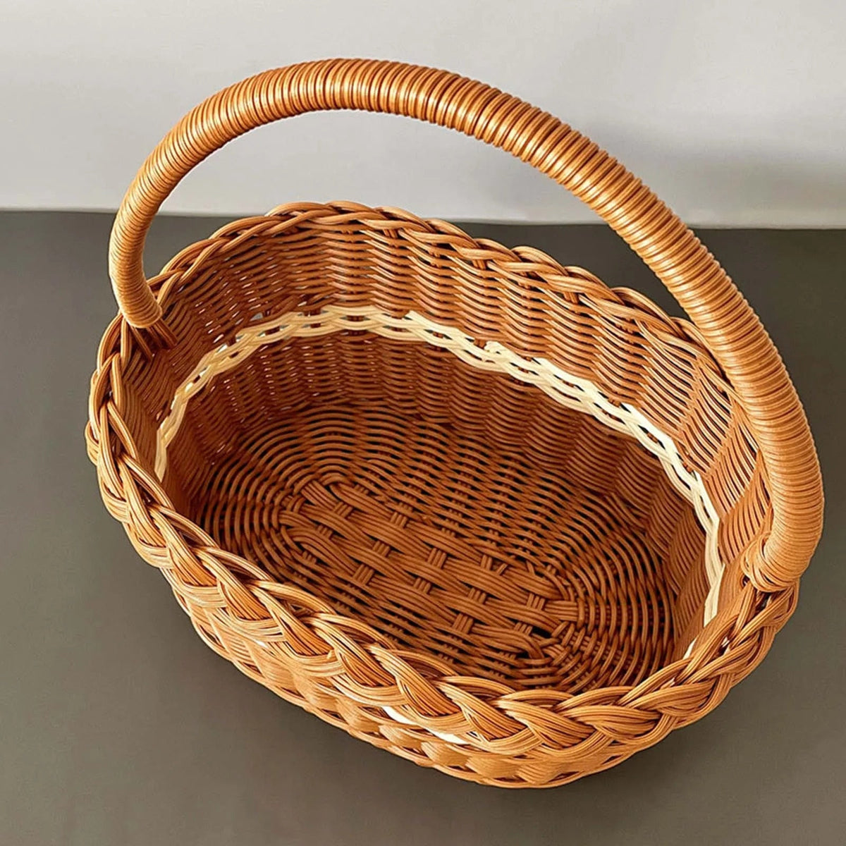 Oval wicker basket with braided rim and arched handle