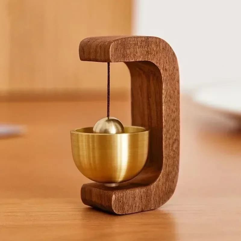 Small brass bell hanging in a curved dark wood frame