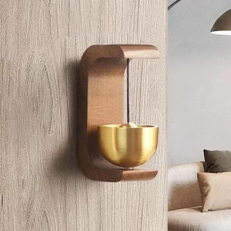 Small brass bell hanging in a curved dark wood frame