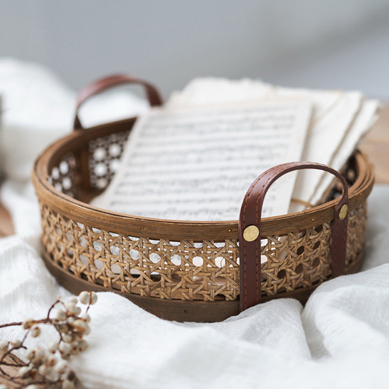 Round brown rattan storage tray with stitched leather handles