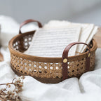 Round brown rattan storage tray with stitched leather handles