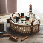 Round brown rattan storage tray with stitched leather handles