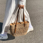 Caramel brown woven straw beach handbag with a braided cord strap