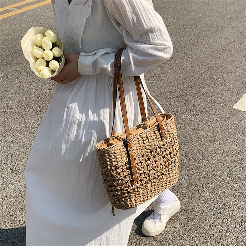 Caramel brown woven straw beach handbag with a braided cord strap