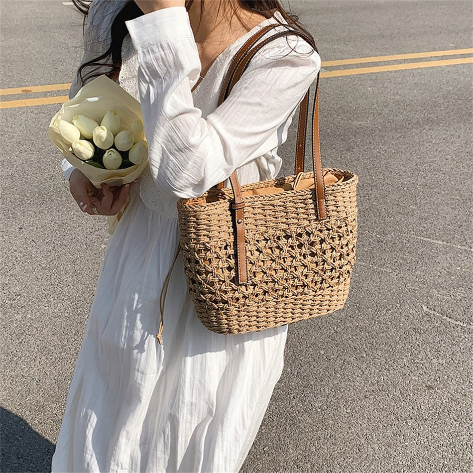 Caramel brown woven straw beach handbag with a braided cord strap