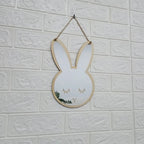 Bunny shaped wooden wall mirror hanging on a white brick wall