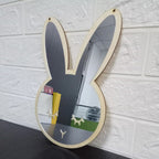 Bunny shaped wooden wall mirror hanging on a white brick wall