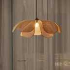 Flower shaped pendant light with woven cane petals over a sofa