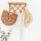Crisscross woven rattan wall coat rack with four hooks and a top shelf
