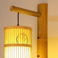 Cylinder bamboo wall sconce with painted motif on a bamboo arm
