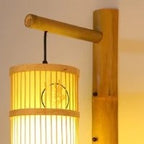 Cylinder bamboo wall sconce with painted motif on a bamboo arm