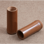 Small dark bamboo tube vase holding dried stems