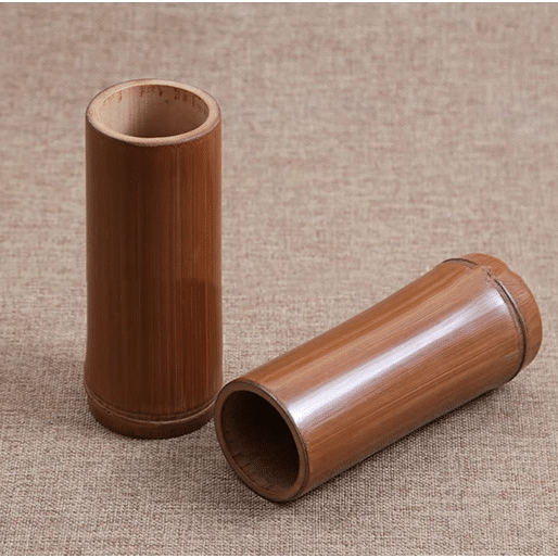 Small dark bamboo tube vase holding dried stems