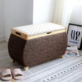 Chocolate brown woven storage stool with a padded floral lid on light wood feet