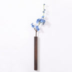 Slim dark wood wall vase holding a single stem