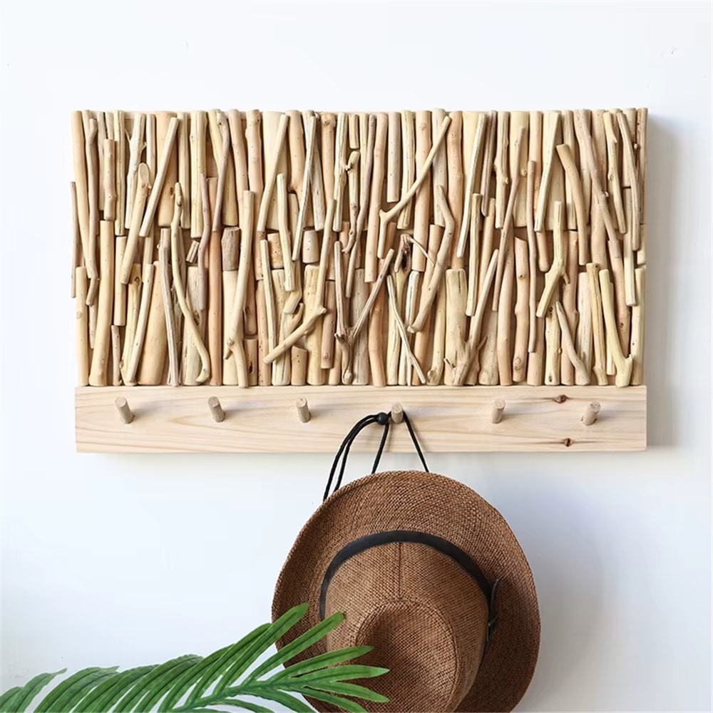 Wall coat rack made of natural driftwood sticks above a wood board with hooks