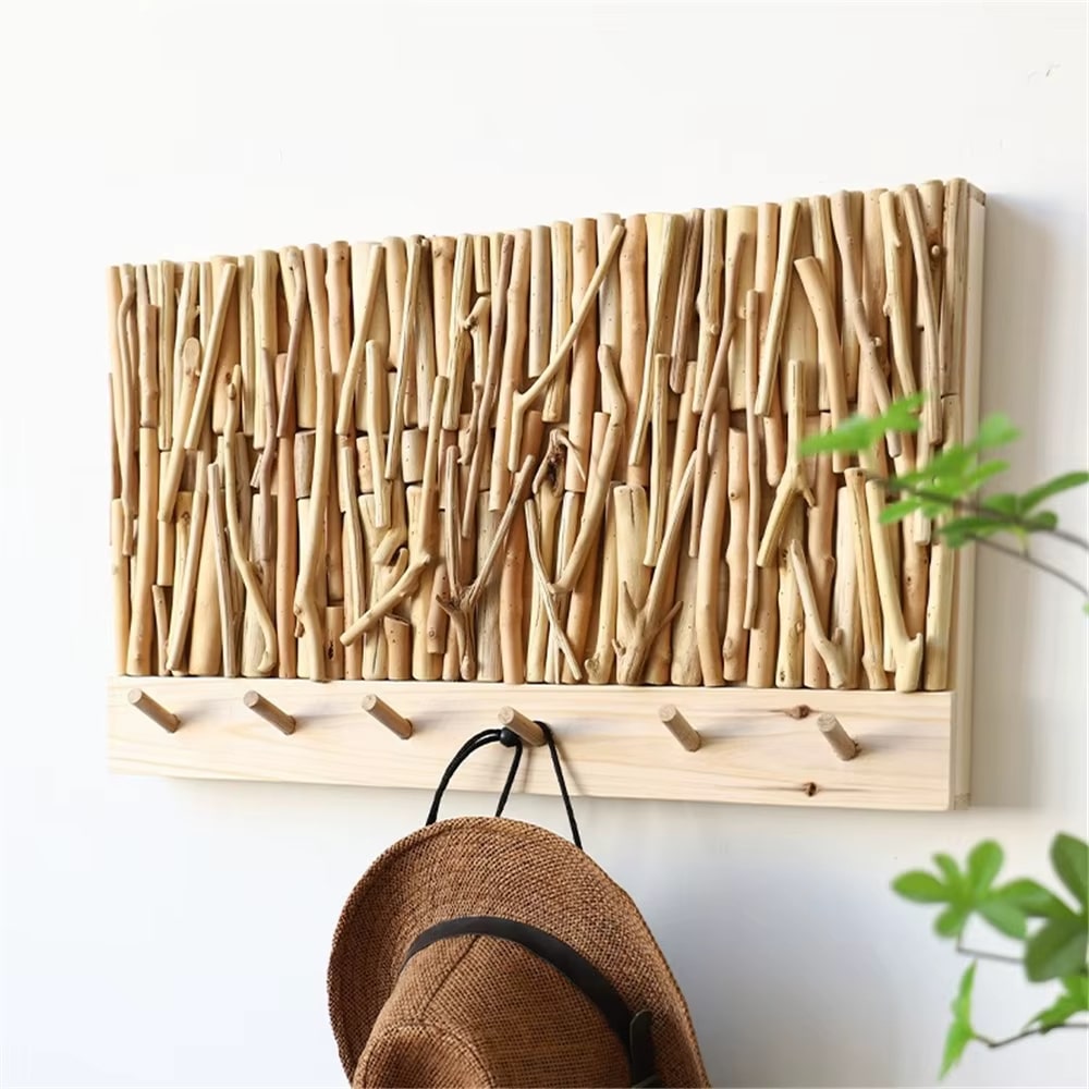 Wall coat rack made of natural driftwood sticks above a wood board with hooks
