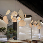 Sculptural chandelier of floating woven bamboo leaf panels over a dining table