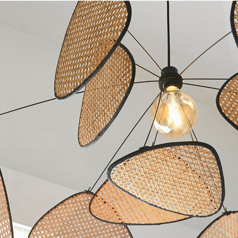 Sculptural chandelier of floating woven bamboo leaf panels over a dining table