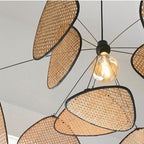 Sculptural chandelier of floating woven bamboo leaf panels over a dining table
