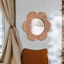 Flower shaped rattan wall mirror above plants