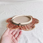 Flower shaped rattan wall mirror above plants