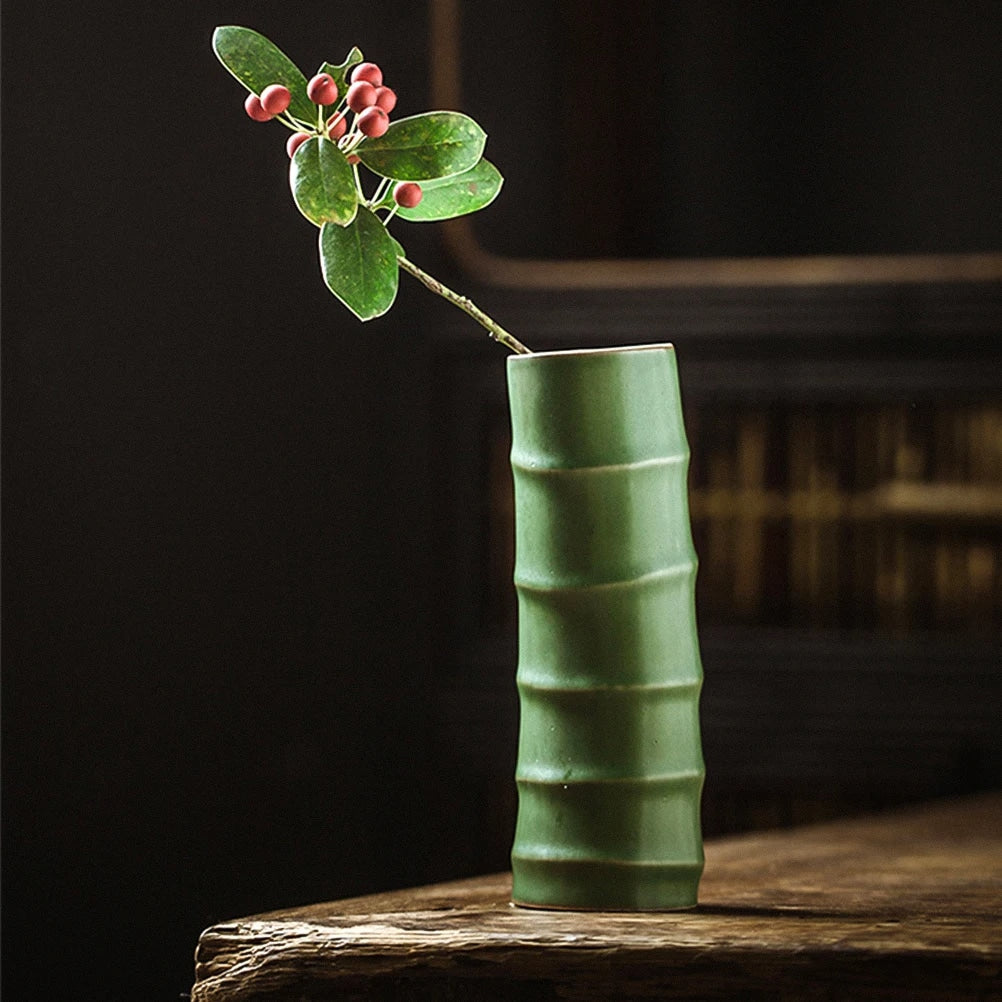 Green ceramic vase shaped like a bamboo stem with a flowering branch
