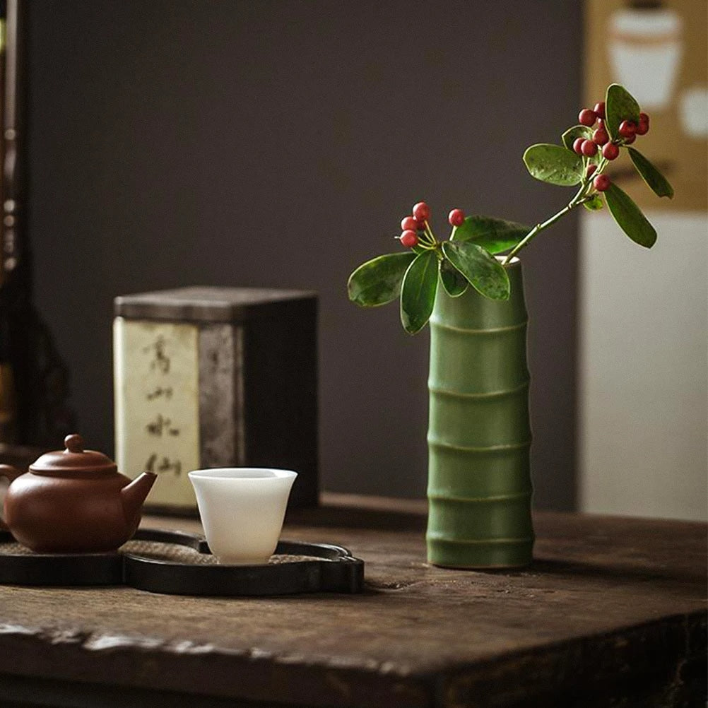 Green ceramic vase shaped like a bamboo stem with a flowering branch