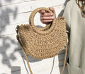 Brown half moon hand woven rattan crossbody bag with an adjustable strap