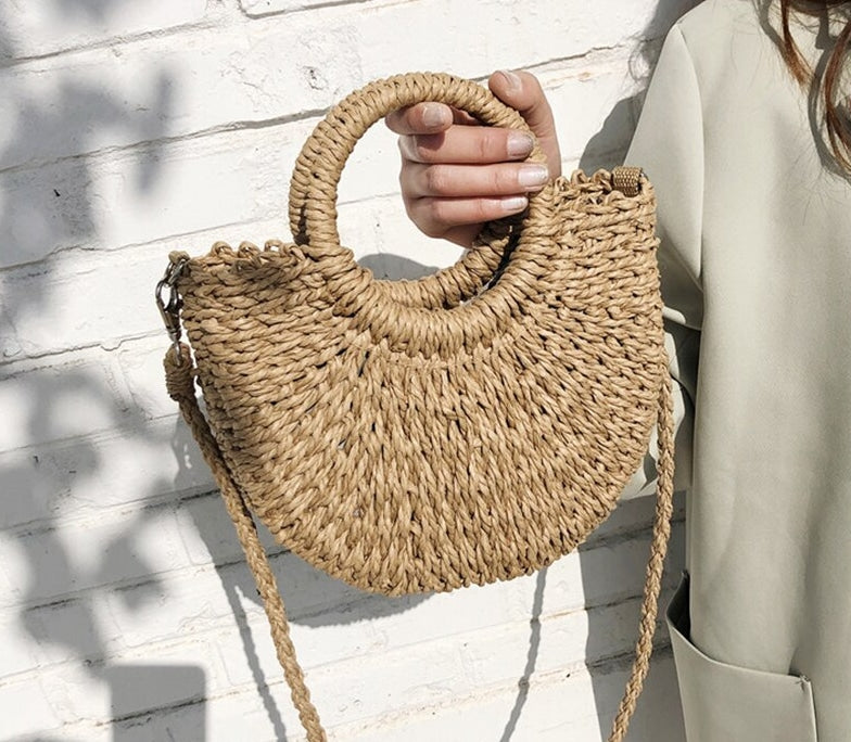 Brown half moon hand woven rattan crossbody bag with an adjustable strap