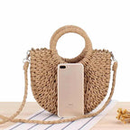 Brown half moon hand woven rattan crossbody bag with an adjustable strap