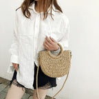 Brown half moon hand woven rattan crossbody bag with an adjustable strap