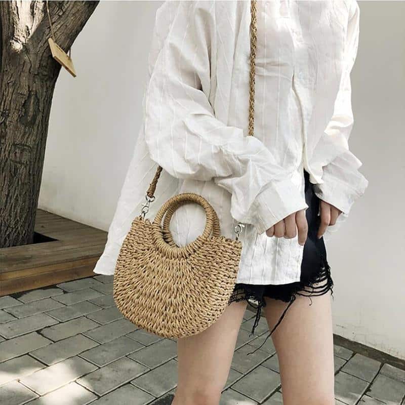 Brown half moon hand woven rattan crossbody bag with an adjustable strap
