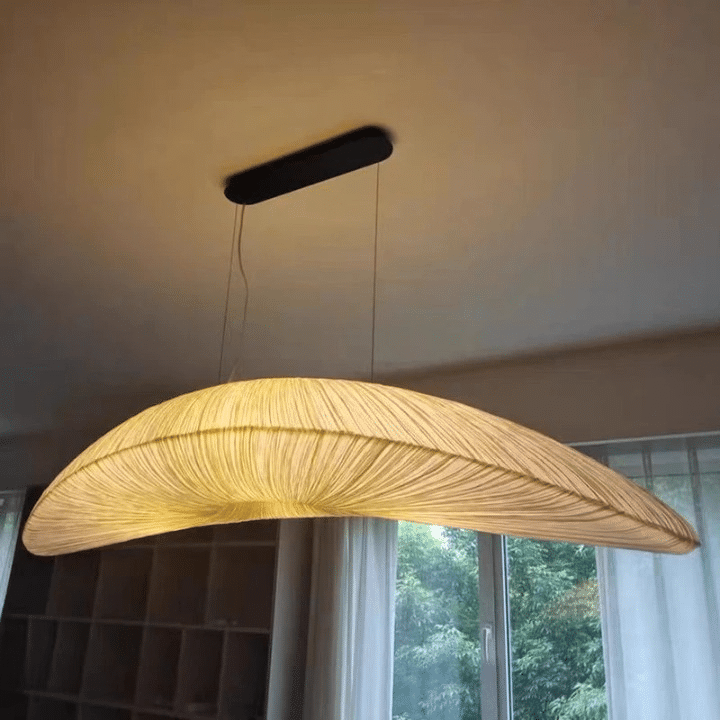 Long rounded pendant light hand knitted in golden straw look fiber on an iron frame