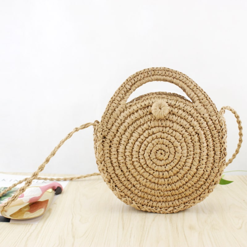 Small rounded hand woven straw crossbody bag in beige and caramel tones