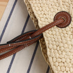 Beige hand woven straw tote with two tone brown handles and a crossbody strap