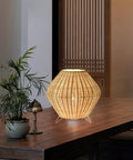 Handmade woven bamboo table lamp with a tapered silhouette and curved top