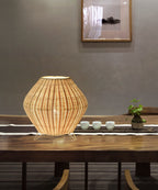 Handmade woven bamboo table lamp with a tapered silhouette and curved top