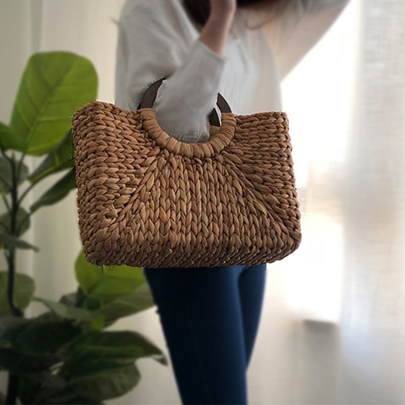Structured hand woven rattan beach bag with a sturdy handle and outer pockets