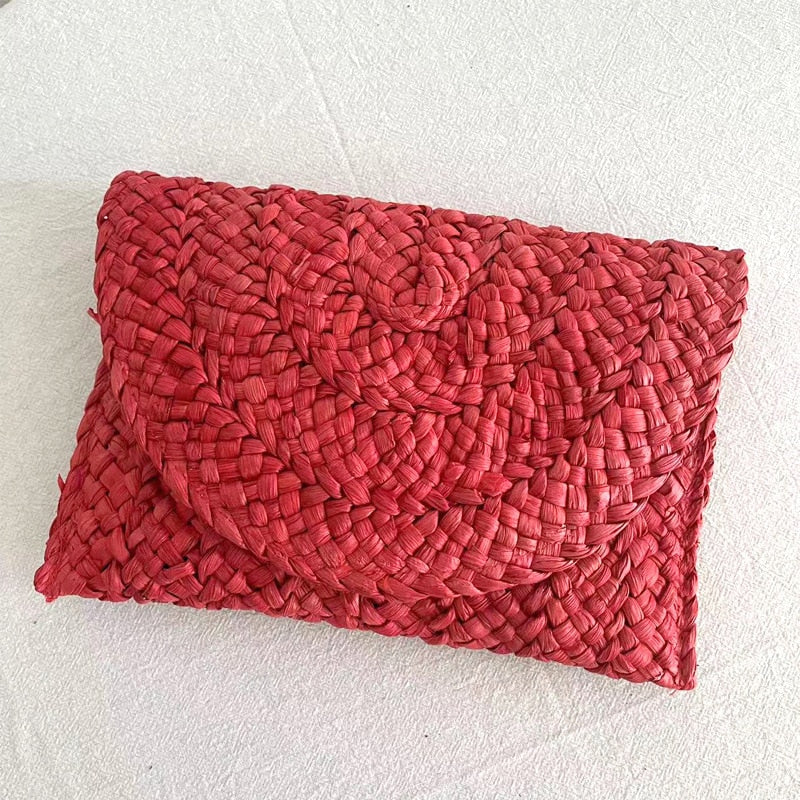 Small handmade woven straw clutch with a colorful pompom, offered in nine colors