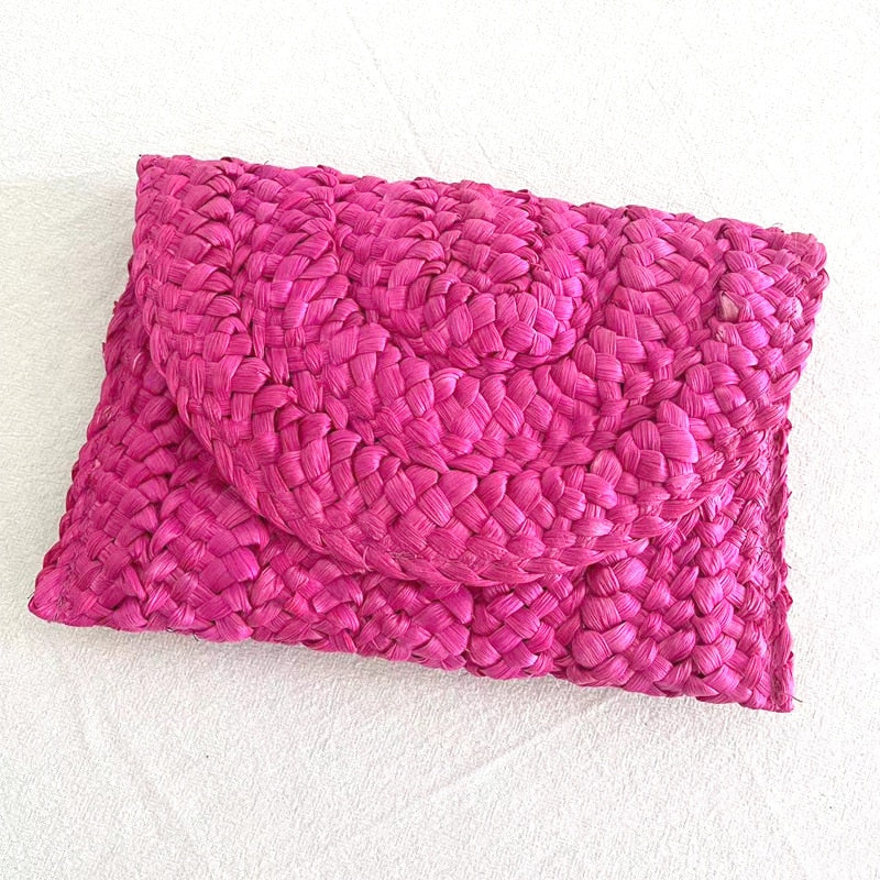 Small handmade woven straw clutch with a colorful pompom, offered in nine colors